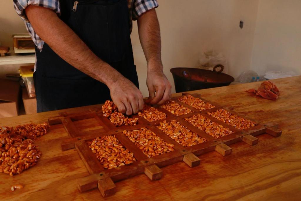 Pueblos mágicos Edomex. Un artesano trabaja en la elaboración de dulces típicos, colocando semillas en un molde de madera sobre una mesa de trabajo.