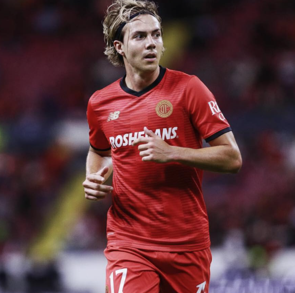 Jugador de fútbol en uniforme rojo en el estadio.