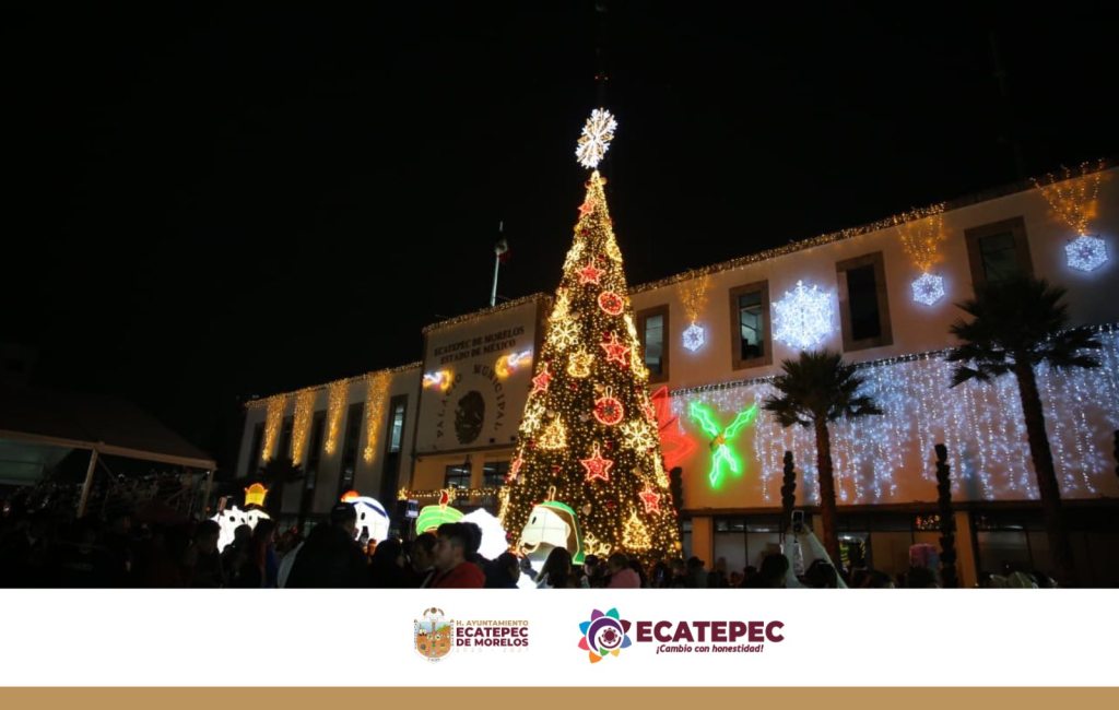 Árbol monumental iluminado en Ecatepec, rodeado de decoraciones navideñas y gente disfrutando de la celebración en la plaza municipal.