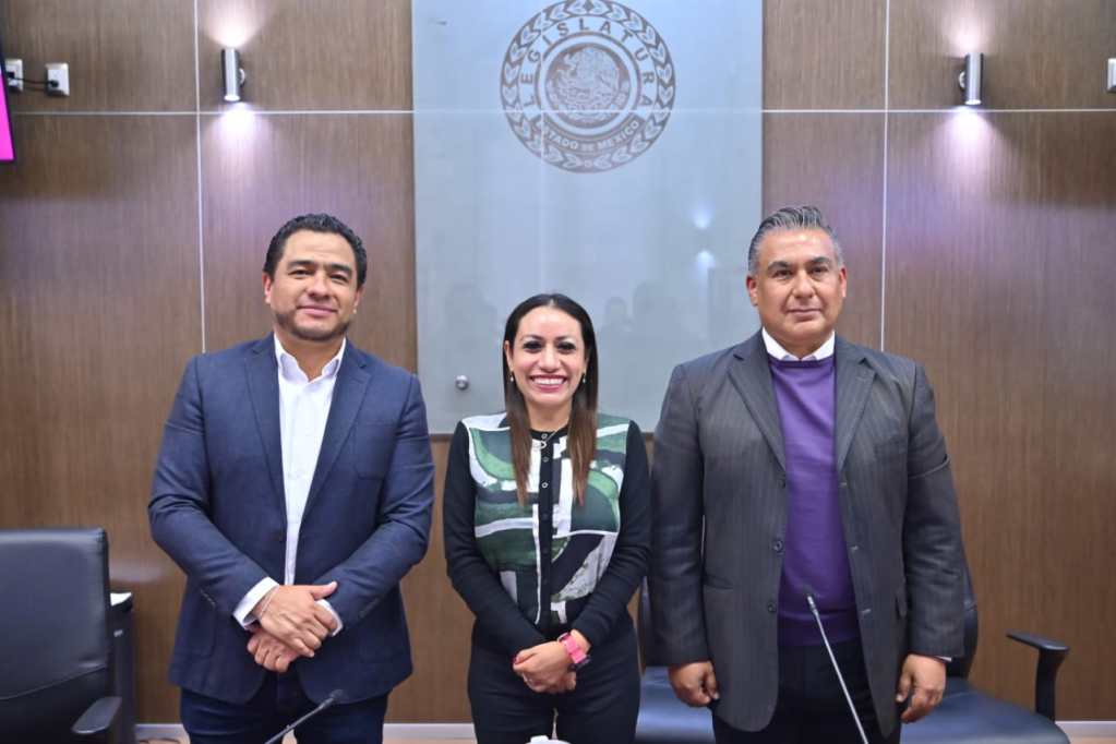 Tres personas posan en un ambiente de oficina, con un fondo que incluye el emblema de la legislatura de México. Dos hombres a la izquierda y derecha, y una mujer al centro, todos sonriendo.