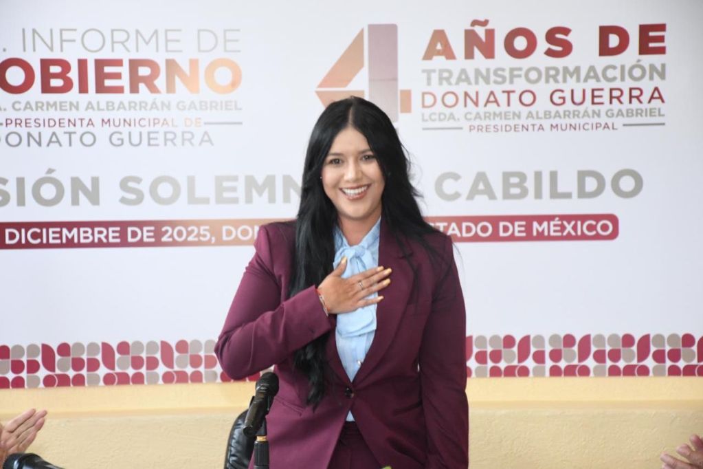 La presidenta municipal Carmen Albarrán, durante su informe de gobierno, sonriendo y con la mano en el corazón, destacando los logros de su administración.