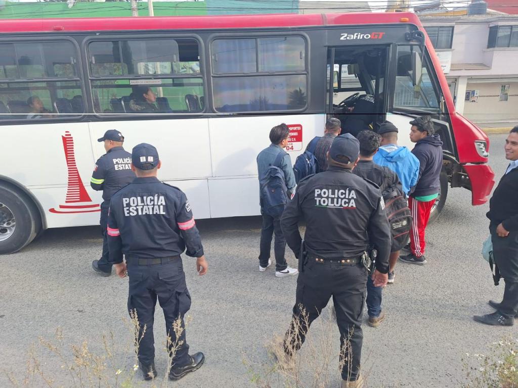 Policías estatales y de Toluca realizan un operativo de seguridad en un autobús con pasajeros en la calle.