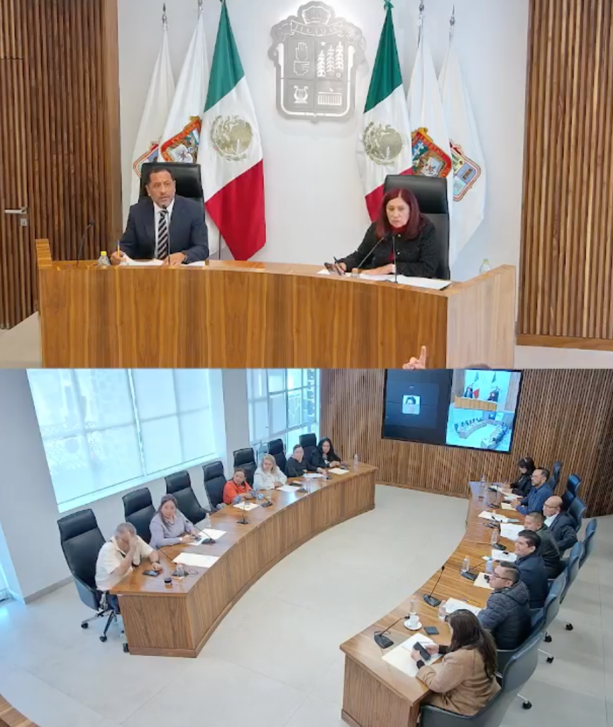 Reunión del Cabildo de Tecámac con miembros sentados en una mesa ovalada y dos funcionarios frente a la cámara en un entorno administrativo.