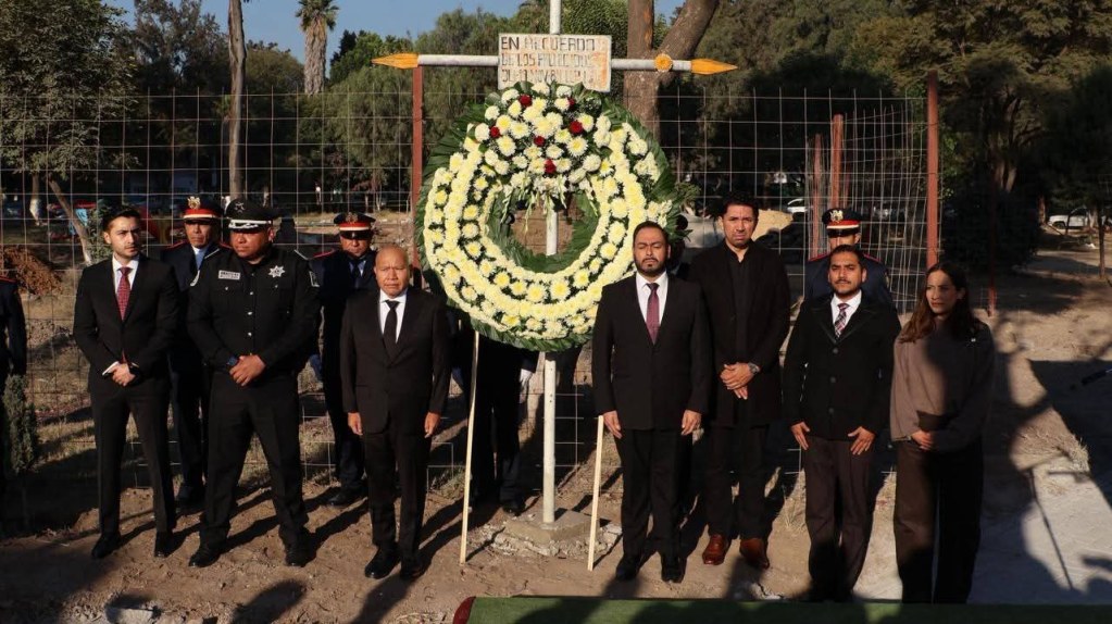 Ceremonia conmemorativa en San Juanico, con un grupo de personas de pie frente a una corona de flores en honor a las víctimas de la explosión de 1984.