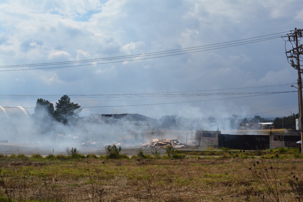 Vista de un área con humo, indicando problemas de contaminación ambiental, posiblemente debido a quema de residuos.