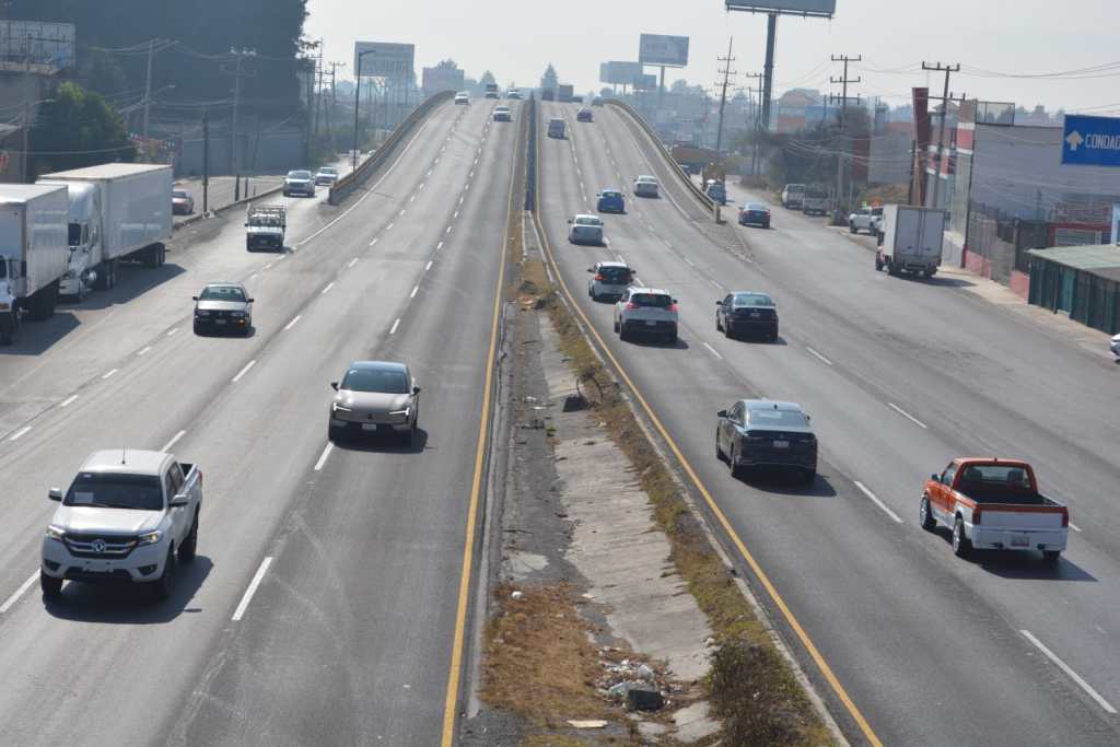 Vista de una carretera con múltiples vehículos en movimiento, incluidos camiones y automóviles, en un día despejado.