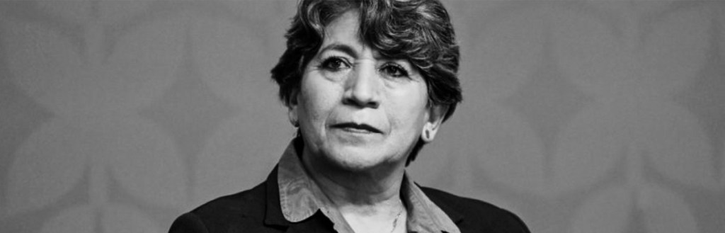 Retrato en blanco y negro de una mujer de mediana edad con cabello rizado y una expresión seria.