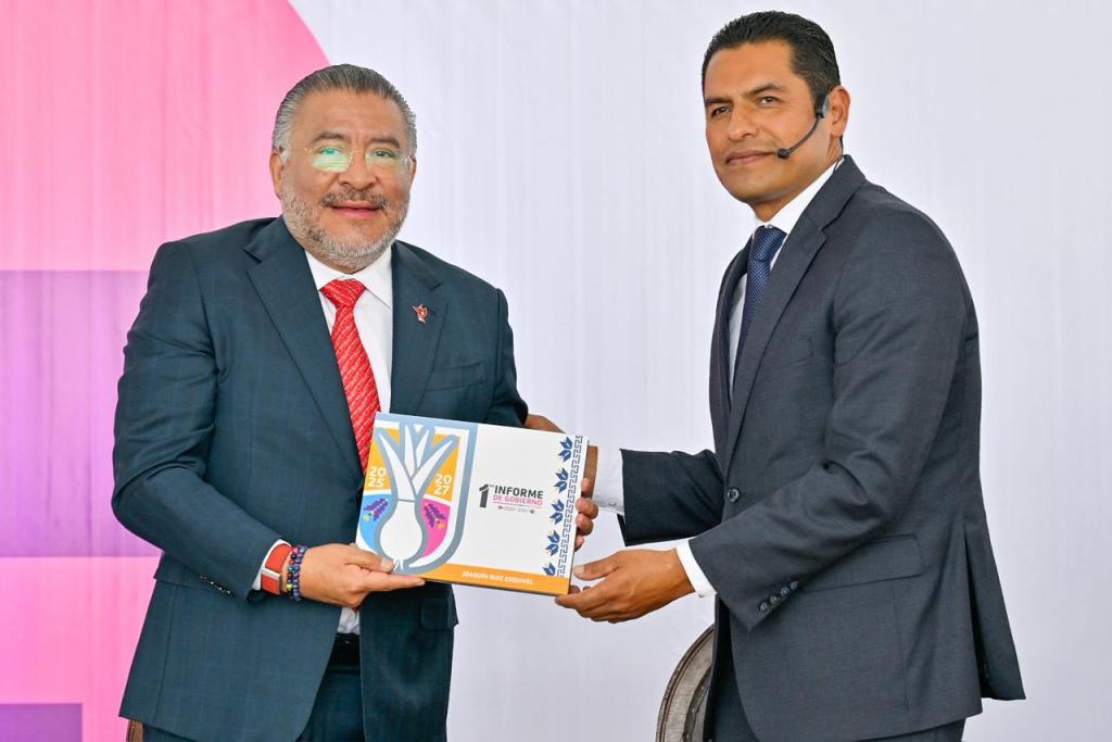 Horacio Duarte Olivares y Miguel Ángel Ramírez Ponce intercambiando documentos en un evento oficial.