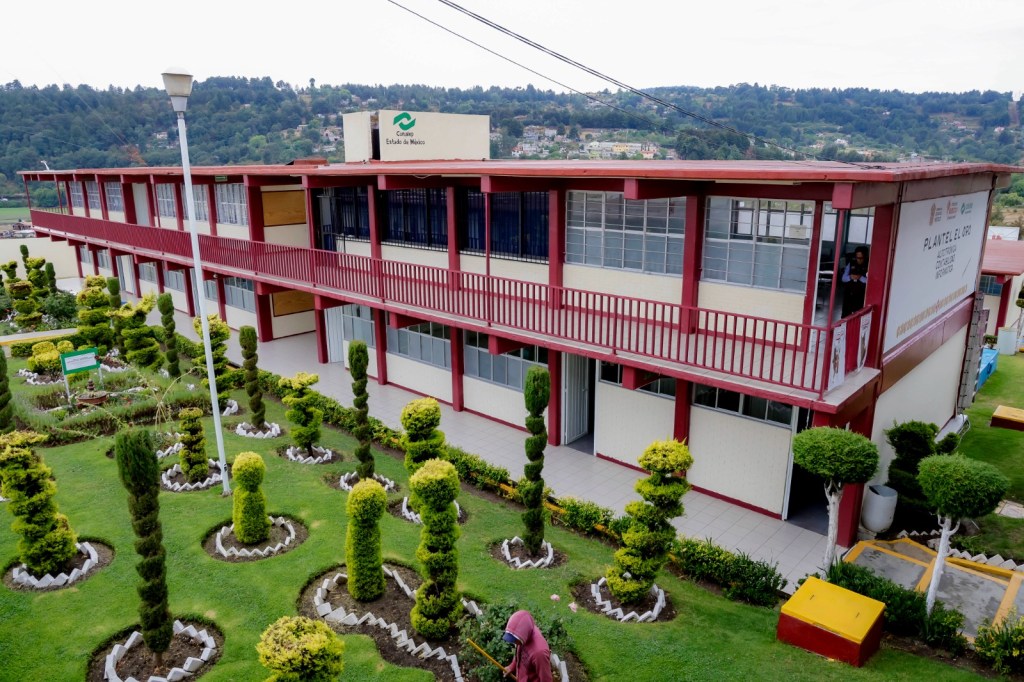 Vista exterior de una escuela en el Estado de México, con un diseño moderno y jardines bien cuidados en el área frontal.