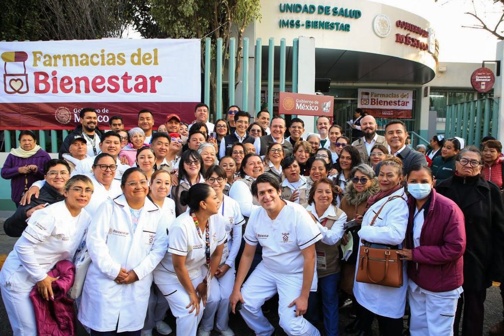 Grupo de personas en una reunión para el lanzamiento del programa Farmacias del Bienestar, con un letrero visible que dice 'Farmacias del Bienestar'.