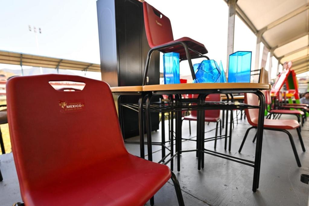 Mobiliario escolar nuevo, incluyendo sillas rojas y mesas, presentado en un evento educativo.