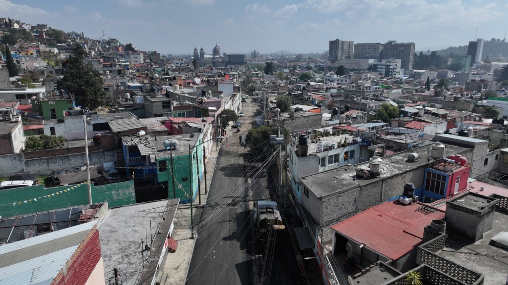 Vista aérea de una calle en Barrios Tradicionales, mostrando casas de diversos colores y una vía en proceso de asfaltado.