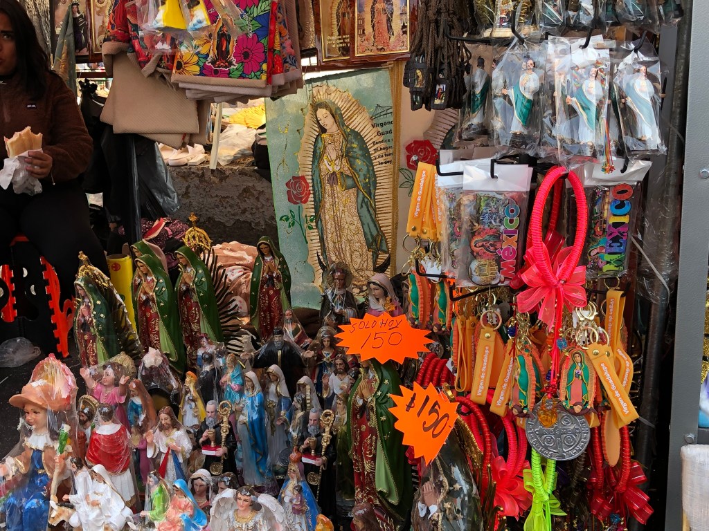 Puestos de venta con artículos religiosos, incluyendo estatuas de la Virgen de Guadalupe, llaveros y souvenirs, en un mercado cerca de la Basílica de Guadalupe.