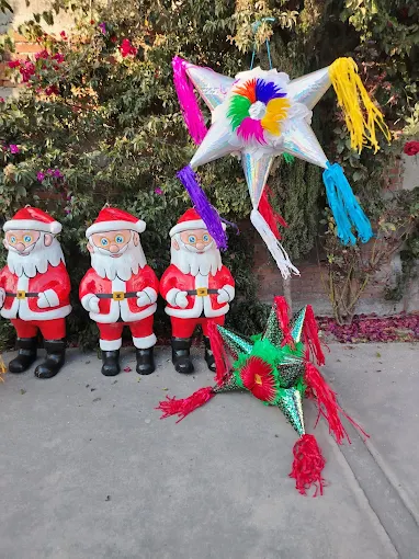 Tres figuras de Santa Claus de pie junto a una piñata en forma de estrella colorida colgando en un entorno navideño.