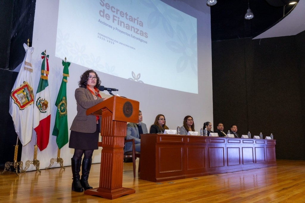 Presentación de la Secretaría de Finanzas en el Auditorio 'Ing. José Yurrieta Valdés', con la rectora Martha Patricia Zarza Delgado hablando frente a un podio y una mesa con varios representantes.