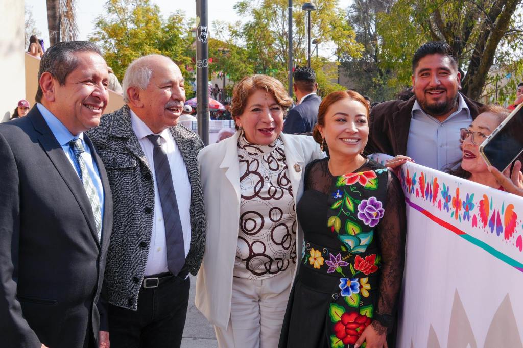Grupo de personas sonrientes posando juntos, con un fondo decorativo que incluye elementos coloridos y tradicionales.