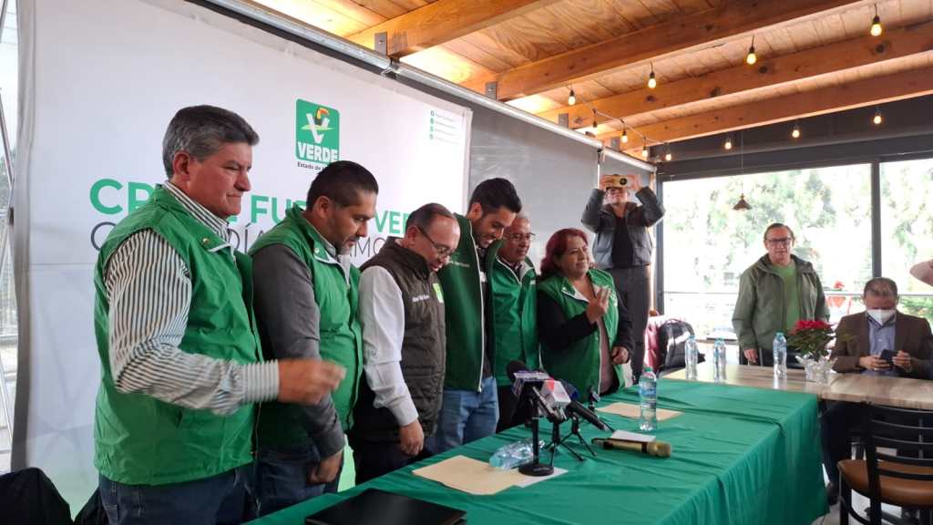 Evento de adhesión de políticos al Partido Verde Ecologista de México en Zinacantepec, con miembros en el escenario y una presentación institucional de fondo.
