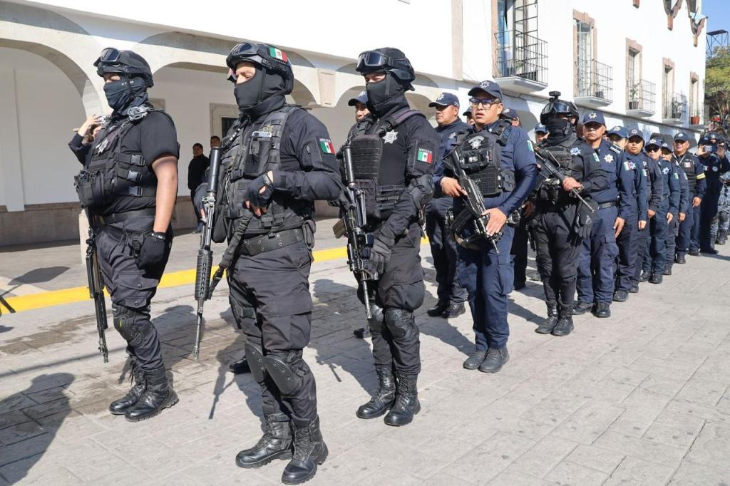 Un grupo de policías vestidos de negro en formación, equipados con armas, durante un operativo de seguridad en un espacio público.