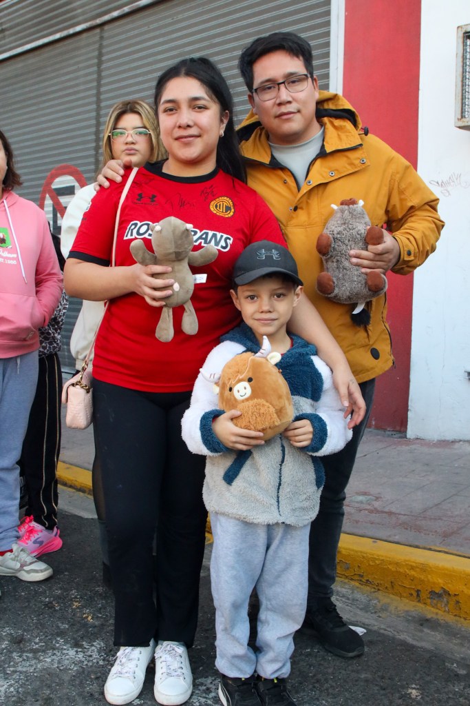 Familia posando con peluches en un evento benéfico para el Día de Reyes, con un ambiente festivo y solidario.