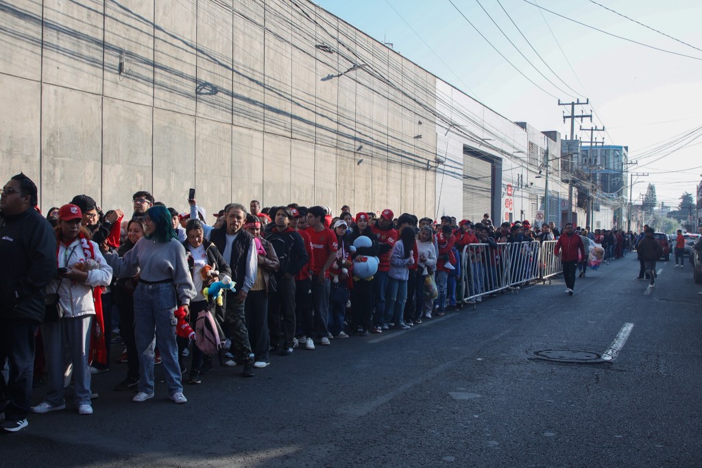 Multitud de aficionados del Toluca FC en fila, esperando para entrar al estadio y donar juguetes durante un evento especial de entrenamiento.