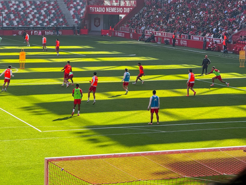 Jugadores del Toluca FC entrenando en el Estadio Nemesio Diez, rodeados de aficionados que observan desde las gradas.