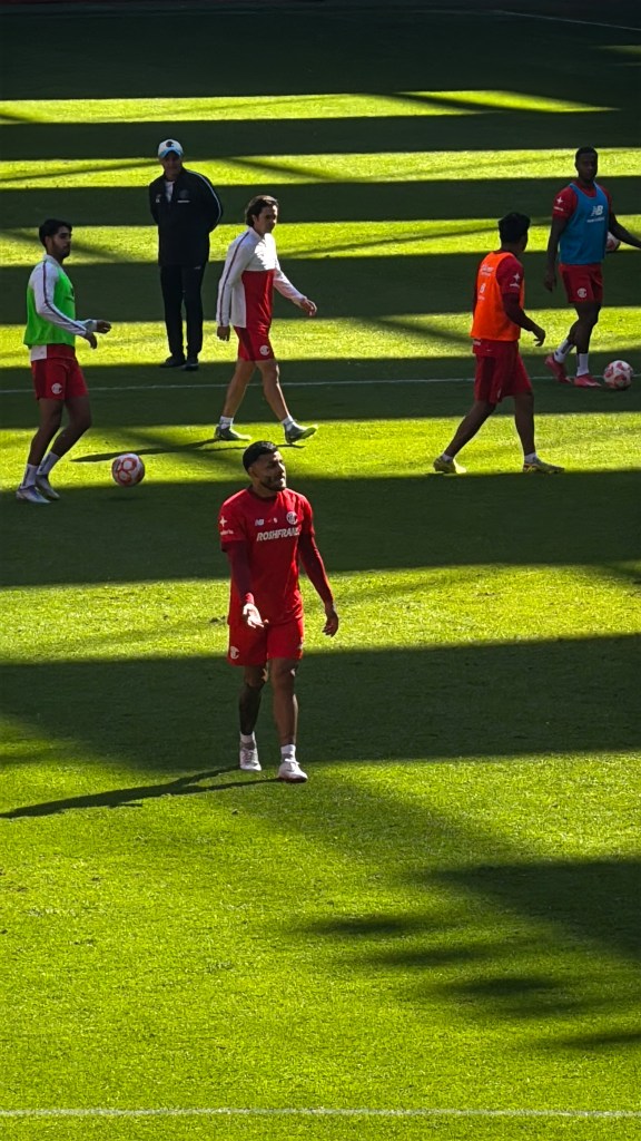 Jugadores del Toluca FC durante un entrenamiento en el Estadio Nemesio Diez, con luz natural y sombras sobre el campo.