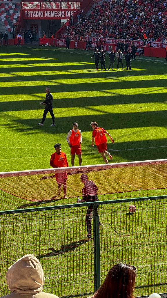 Jugadores del Toluca FC entrenando en el Estadio Nemesio Diez, con la afición en las gradas. Se observa un ambiente festivo y solidario.