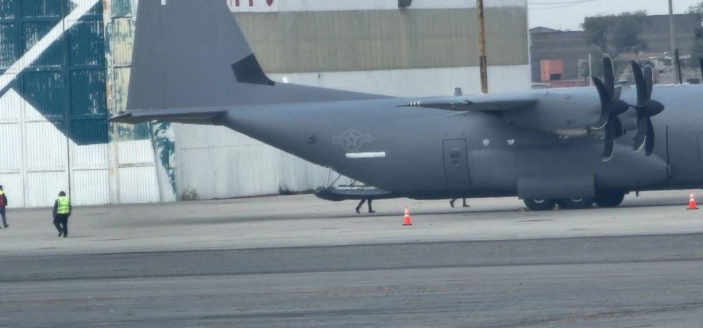 Military aircraft on a tarmac with personnel in reflective vests walking nearby.