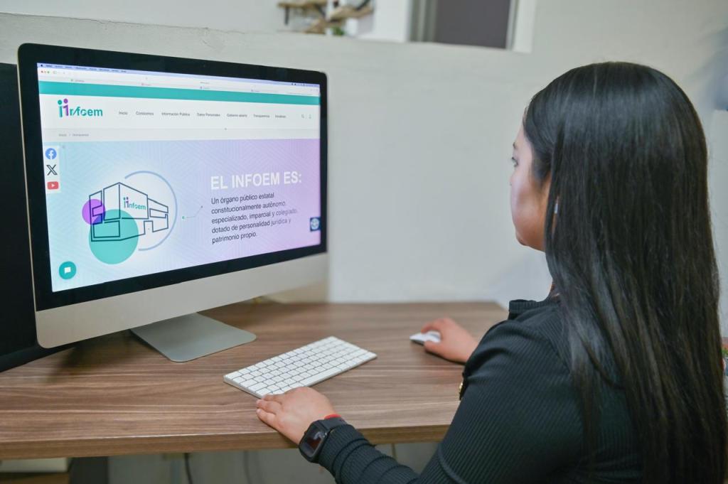 Una persona sentada frente a un monitor de computadora, visualizando la página web del INFOEM, que describe su función como un órgano público estatal con autonomía.