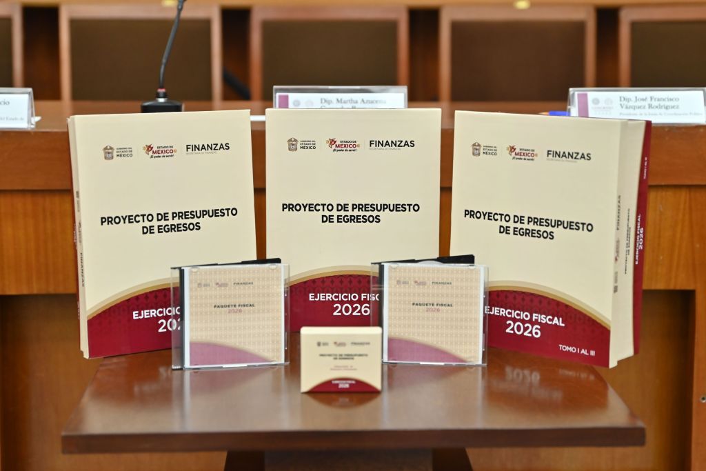 Tres libros titulados 'Proyecto de Presupuesto de Egresos 2026' y dos CD sobre el presupuesto, colocados sobre una mesa en el Congreso del Estado de México.