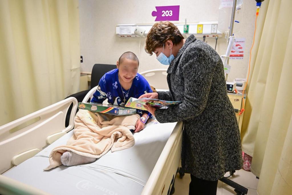 La gobernadora Delfina Gómez Álvarez interactuando con un niño en cama de hospital, sosteniendo un libro y sonriendo en un ambiente hospitalario.