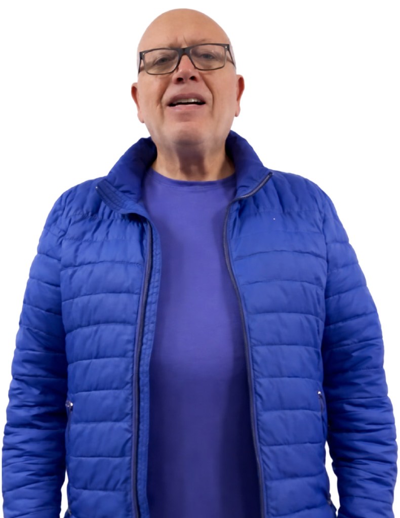 Hombre mayor con gafas y chaqueta azul, sonriendo y hablando frente a un fondo blanco.