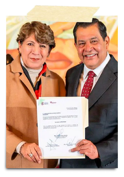 Una mujer y un hombre sosteniendo un documento firmado, sonriendo en un evento formal.