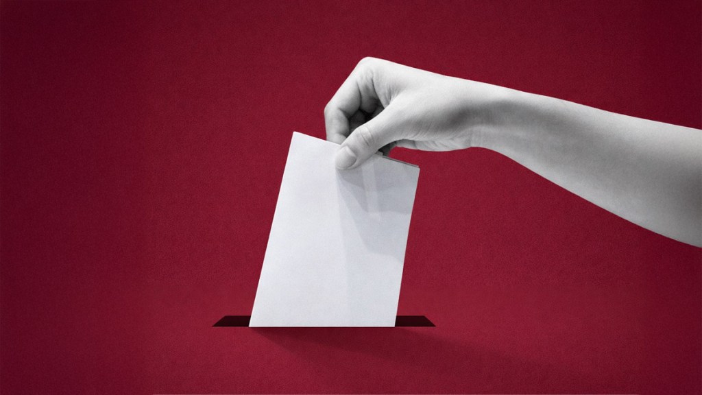 Una mano colocando una boleta en una caja de votación sobre un fondo rojo.