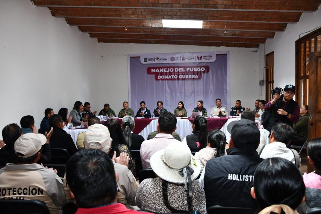 A meeting in a conference room discussing fire management, featuring a panel of speakers at the front and an audience facing them.