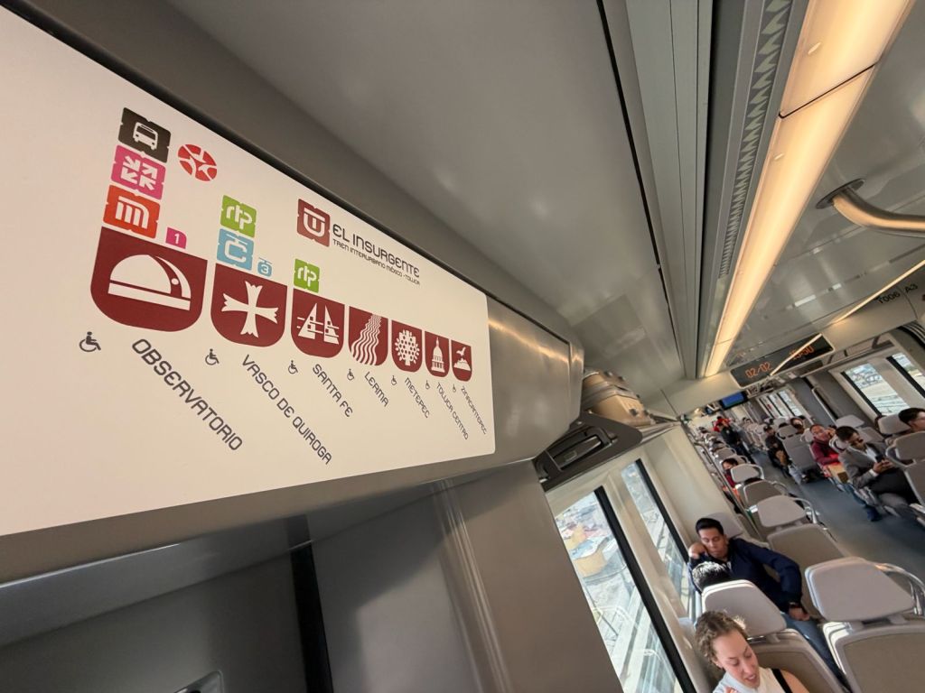 Interior view of a modern train car, featuring a route map for the El Insurgente transit line. The map highlights stops such as Observatorio and Vasco de Quiroga, with symbols indicating accessibility options.