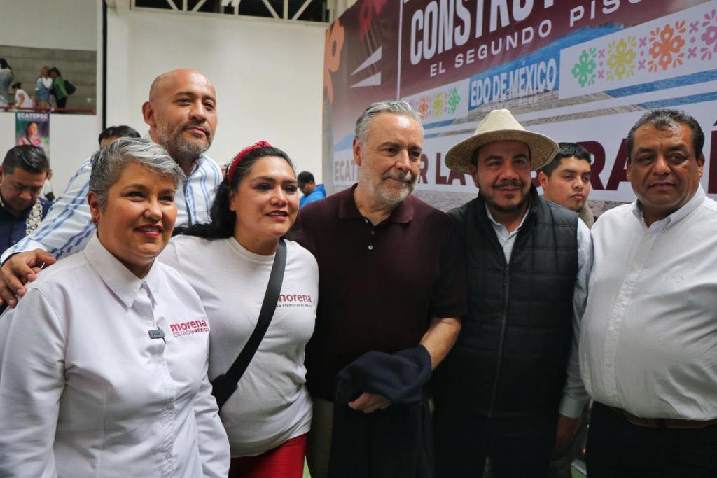 Grupo de personas posando para una foto en un evento político, algunas con camisetas de Morena, en un ambiente festivo.