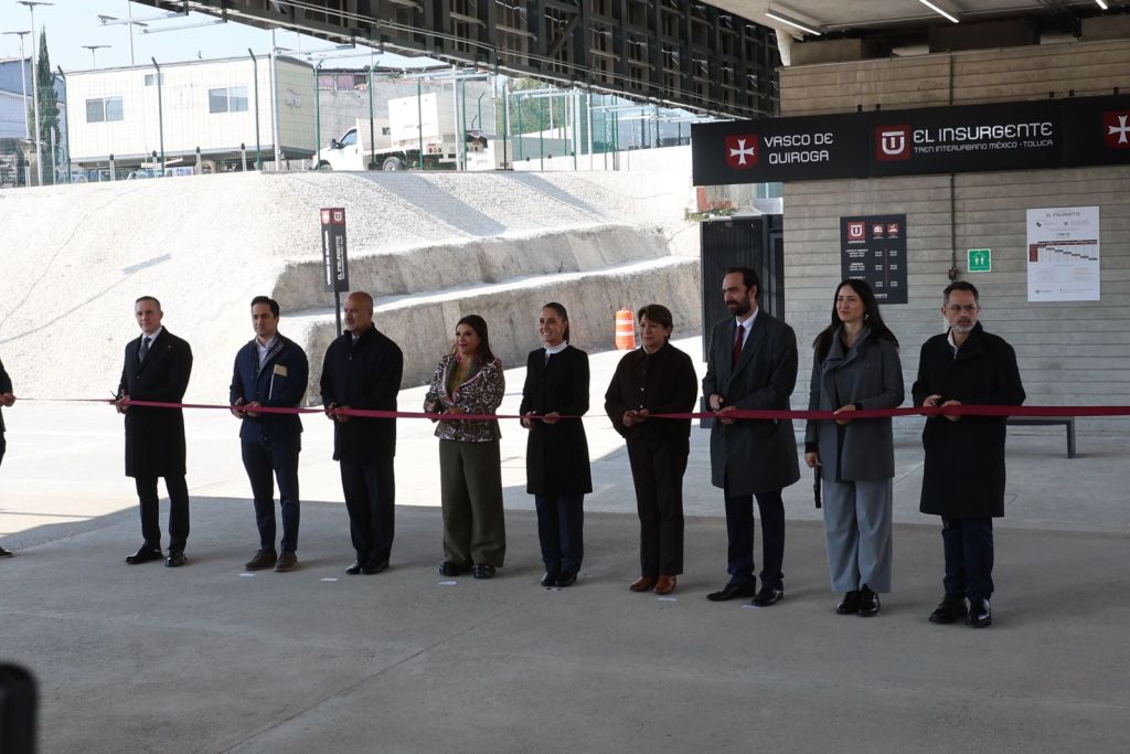 A group of people holding a ribbon for a ceremonial ribbon-cutting event at a transportation hub, featuring a sign for 'Vasco de Quiroga' and 'El Insurgente'.