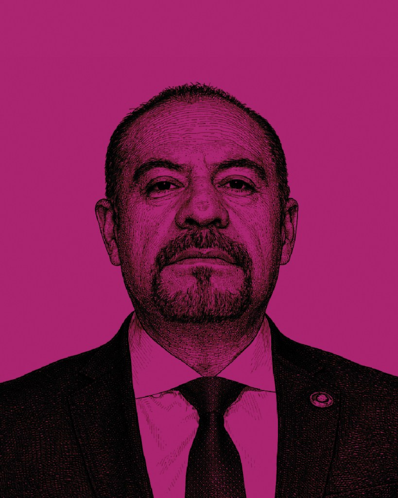 Retrato de un hombre con cabello oscuro y barba, vestido con traje y corbata, sobre un fondo rosa.