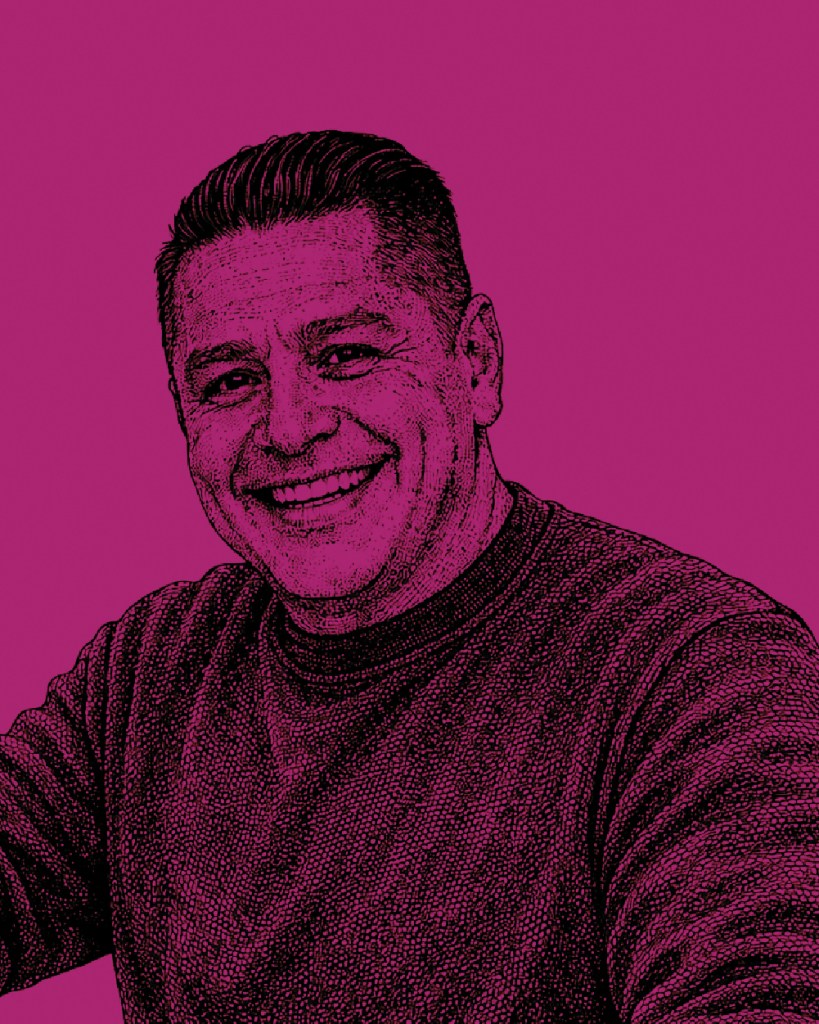 Retrato de un hombre sonriente con una camiseta de manga larga, sobre un fondo rosa vibrante.