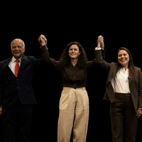 Representantes de Morena, PT y PVEM levantando las manos en señal de unidad sobre fondo negro durante evento rumbo al 2027.