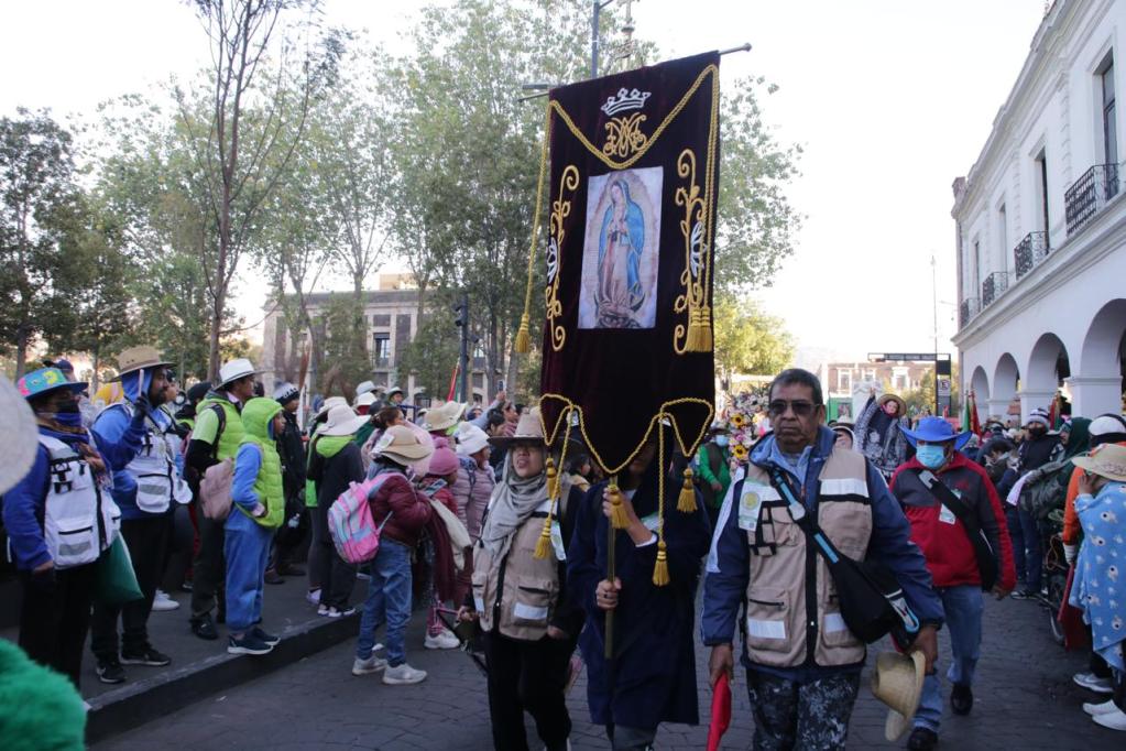 Grupo de personas en una celebración, con un estandarte de la Virgen y diversas vestimentas.