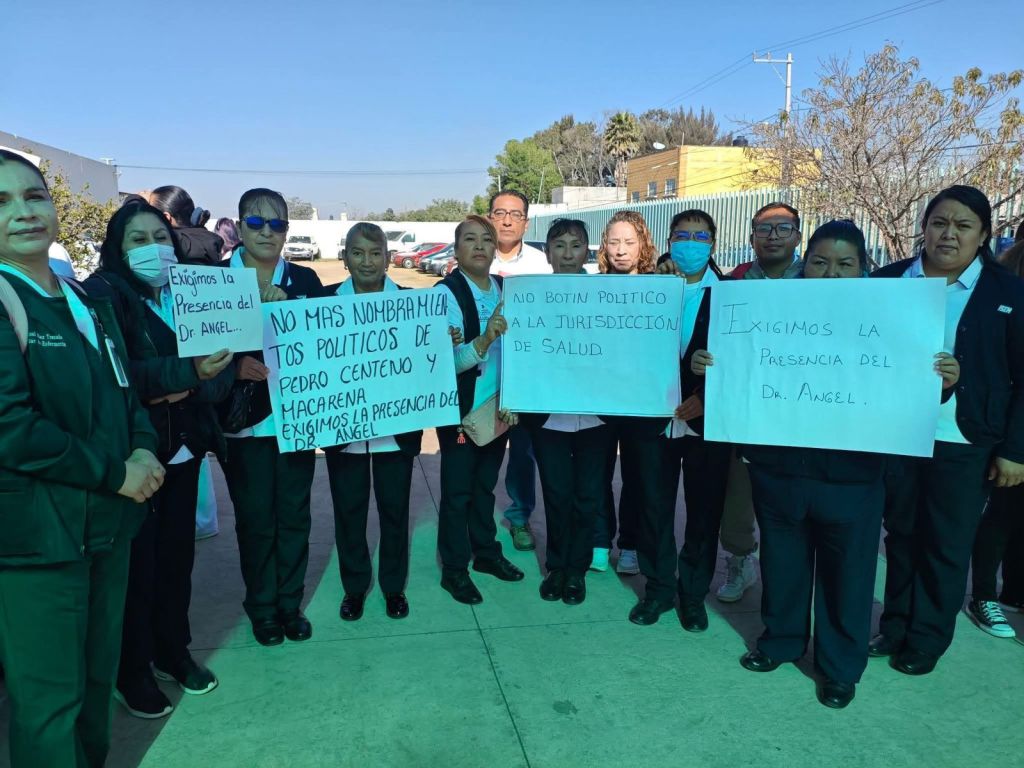 Group of health workers holding signs demanding the presence of Dr. Angel and protesting against political appointments.
