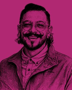 Retrato de un hombre sonriente con barba y bigote, usando gafas y una chaqueta sobre una camisa, contra un fondo rosa.