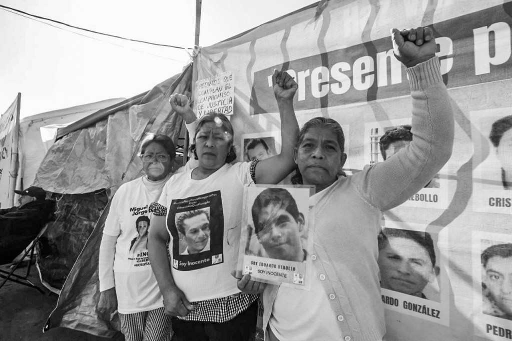 Tres mujeres sosteniendo carteles con fotos de personas desaparecidas, en un evento de protesta, mostrando signos de resistencia y justicia.