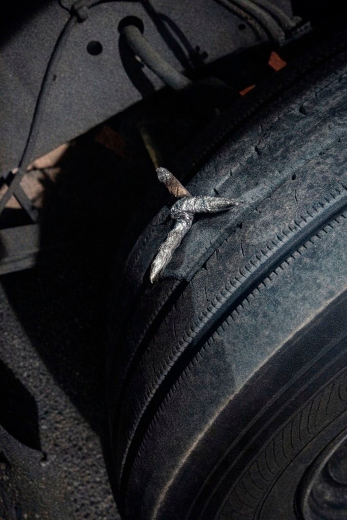 Clavo oxidado incrustado en un neumático desgastado.