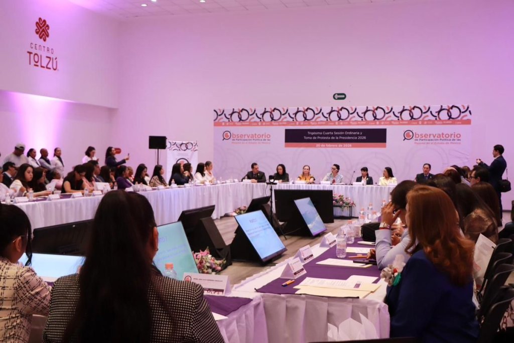 Reunión en el Centro Tolzú con participantes discutiendo en una mesa amplia, decorada con flores y documentos.