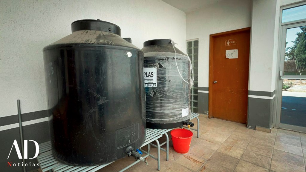 Dos tanques de agua negra en un área interior con una puerta de baño al fondo.