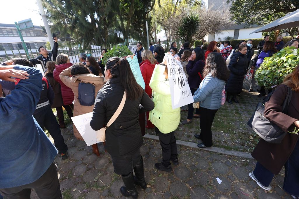 A crowd of people gathered outdoors, some holding signs. They appear to be participating in a protest or demonstration, with a focus on visibility and community engagement.