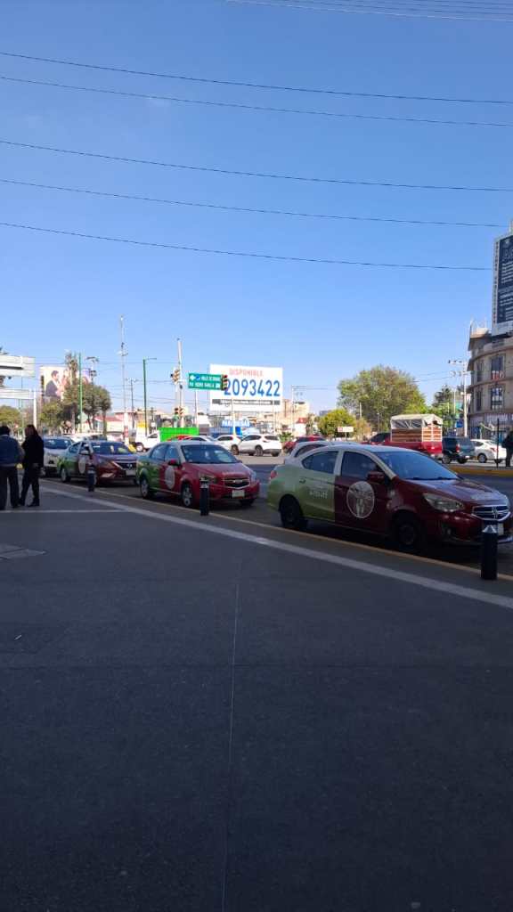 A busy street scene showing several colorful taxis lined up on the road, with a clear blue sky in the background and a large billboard displaying the number 2093422.